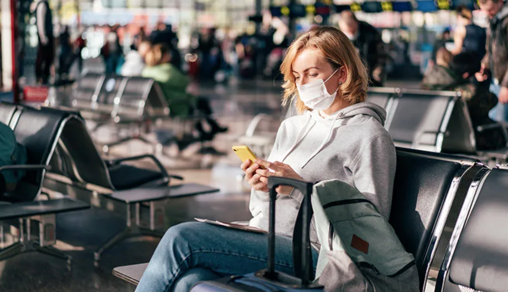 woman sitting at airport wearing a mask